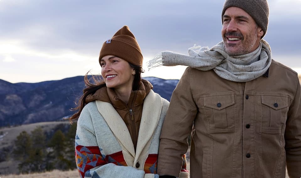 Couple in winter clothing enjoying scenic mountain views outdoors.